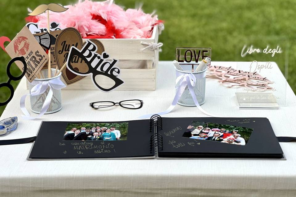 Album aperto con fotografie e dediche degli invitati, accanto agli accessori per il Photo Booth